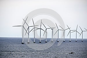 The boat swims by the wind power stations