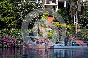 boat tied standing in the middle of beautiful flower and tree shaded cove with blue railings showing the beautiful