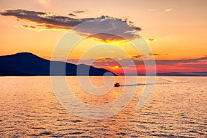 Boat to the sea at sunset in the background of mountains and sun beams, run from Keramoti city to Thassos island in Greece