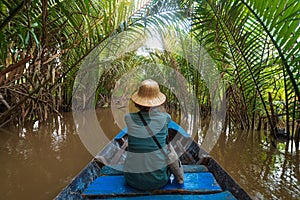 Boat tour in the Mekong River Delta region, Ben Tre, South Vietnam. Tourist with vietnamese hat on cruise in the water canals
