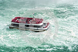 A boat with tourists is driving close to the famous `The Horseshoe Falls`