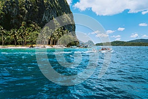 Boat with tourists on ipil beach of exotic island on hopping tour, Bacuit archipelago, El Nido, Palawan , Philippines