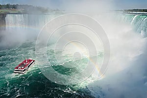 Boat with tourists sailing under the rainbow towards Niagara falls photo