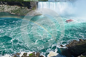 Boat with tourists sailing under the rainbow towards Niagara falls photo
