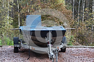 Boat on a trailer covered with a blue cover.