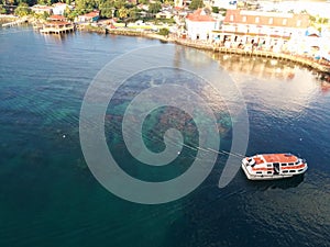 Boat travels over clear sea and coral toward shore