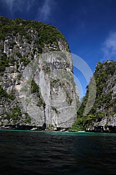 Boat trip around impressive steep rough cliffs of tropical island Ko Phi Phi, Thailand