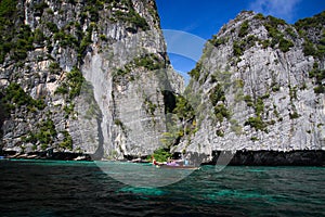 Boat trip around impressive steep rough cliffs of tropical island Ko Phi Phi, Thailand