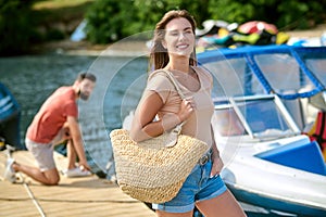 A young womaan standing on the dock while her man untying the boat