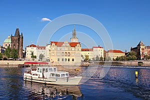 Boat in the Vltava River against background of the old city of Prague on a clear summer day. City landscape of Prague