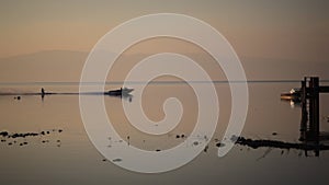 Boat with water skier driving by a pier during sunrise