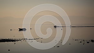 Boat with water skier driving by a pier during sunrise