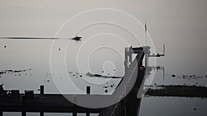 Boat with water skier driving by a pier during sunrise