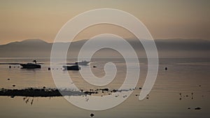 Boat with water skier driving by a pier during sunrise