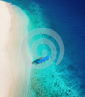 Boat on the water surface from top view. Turquoise water background from top view. Summer seascape from air. Gili Meno island, Ind