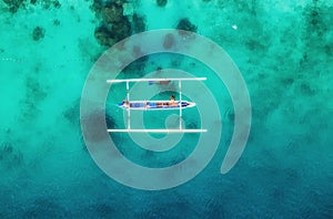 Boat on the water surface from top view. Turquoise water background from top view. Summer seascape from air. Gili Meno island, Ind