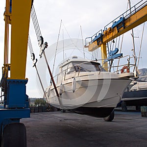 Boat wheel crane elevating motorboat to yearly paint