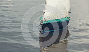 Boat with white sails floating in the water close up.