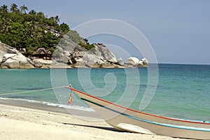 A boat at the white sand beach of the tropical blue sea. Daytime, Koh Phangan, Thailand