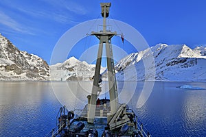 Boat in winter Arctic. White snowy mountain, blue glacier Svalbard, Norway. Ice in ocean. Iceberg twilight in North pole. Pink cl