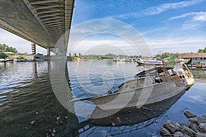 Boat wreck underneath the bridge over Ada and water pollution around it