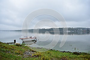 Boat yacht sailboat with motor on river, lake fog over water clouds, green