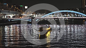 A boat with yellow light inside and the view of the citylights of Tokyo Japan