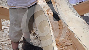 Boatbuilder using adze to carve wooden sailboat