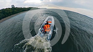 Boatman driving on inflatable boat on water. Man floats on a motorboat