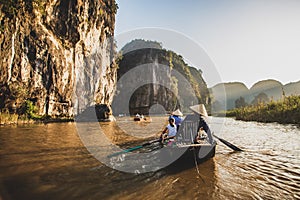 A boatman ferries tourists along the Halong Bay on land tourist attraction in Tam Coc, Vietnam.