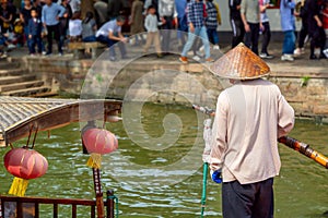 Boatman with paddle near traditional tourist boat on canal of Shanghai Zhujiajiao Old Town in Shanghai, China. Chinese Venice