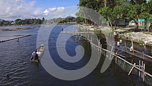 Boatman paddle tiny wooden fishing boat on mountain lake. Drone aerial