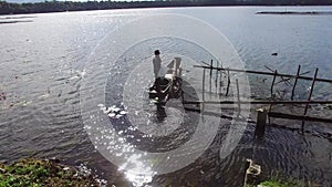 Boatman paddle tiny wooden fishing boat on mountain lake. Drone aerial