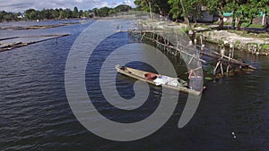 Boatman paddle tiny wooden fishing boat on mountain lake. Drone aerial