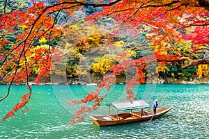 Boatman punting the boat at river. Arashiyama in autumn season along the river in Kyoto, Japan photo
