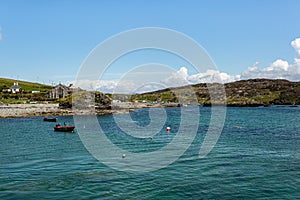 Boats and buoys in the bay, the rocky shoreline with its small harbor, its church on Inishbofin Island photo
