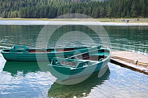 Boats on calm lake water. Green wooden boats.