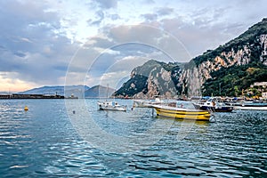 Boats in Capri island main harbor under cloudy skies