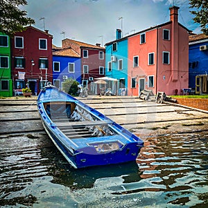 Boats and colorful traditional painted houses in a canal street houses of Burano island