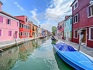 Boats and colorful traditional painted houses in a canal street houses of Burano island