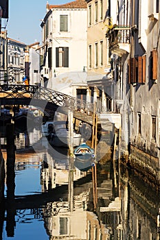 Boats covered from rain parked in the water next to the house in canal of Venice.