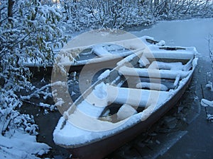 Boats covered in snow on frozen lake