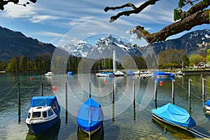 Boats covered with tarpaulin moored on Walensee lake. View of the Alps. Weesen, Switzerland