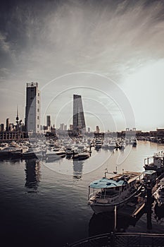 Boats docked at a pier with an urban skyline in the backdrop: Arabian Gulf , Kuwait