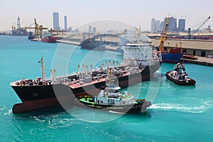 Boats docked to industrial ship in port sail photo