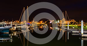 Boats and docks reflecting in the water at night, at a marina on