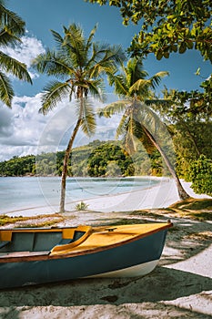 Boats on exotic beach Takamaka with Palm trees und blue ocean lagoon in background, Mahe island, Seychelles