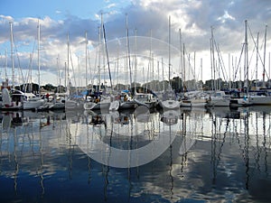 Boats in a harbor mirrored on water surface