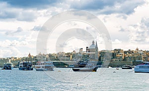 Boats in harbor of Valletta, capital of Malta. Scenic view of maltese coast with ships and traditional houses. Popular famous