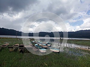 Boats on the lake. Tranquil nature view with gloomy sky and cloud reflections on the water